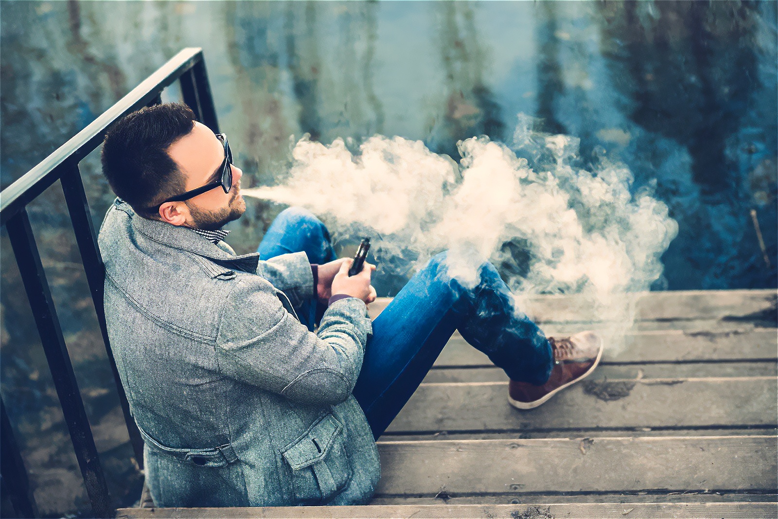 Парень в стрессовом состоянии курит айкос